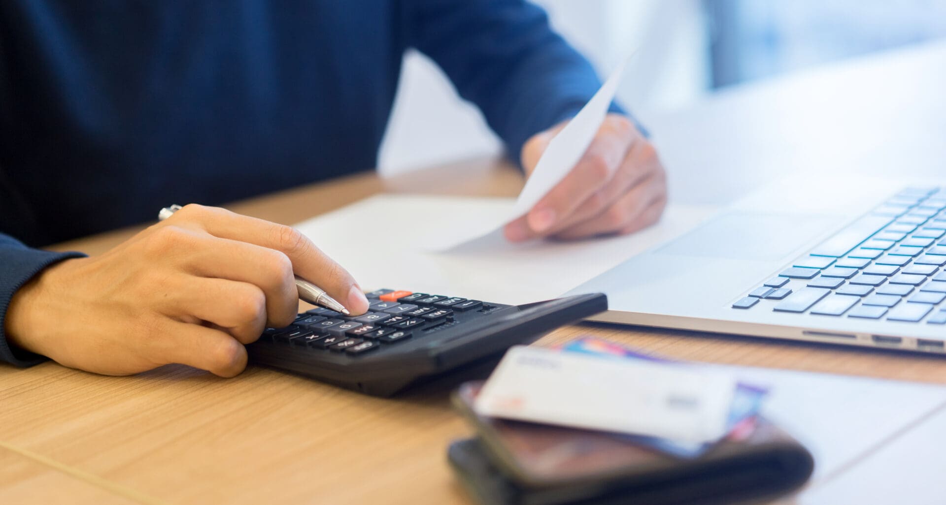 Close,Up,Man,Hand,Writing,On,Notebook,And,Calculating,On