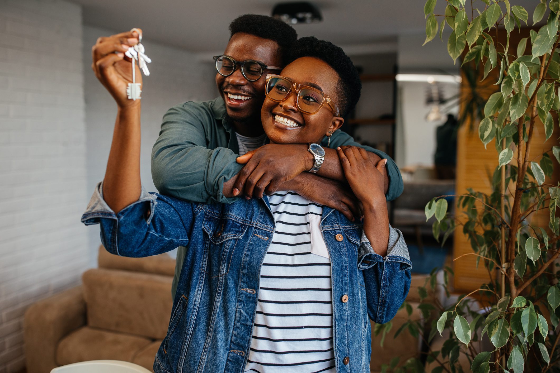 Couple embracing in the living room and holding keys of their new home